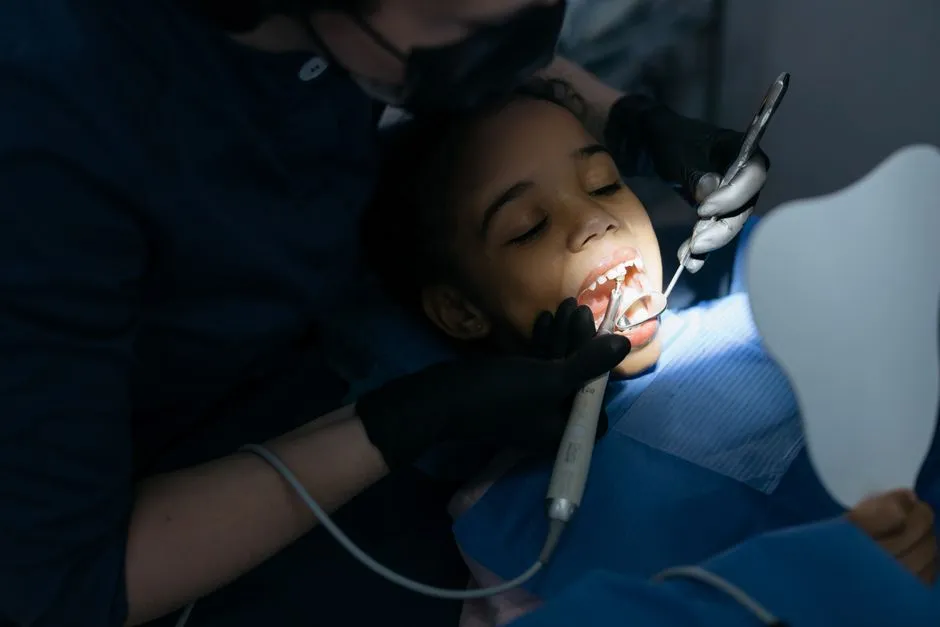 Pediatric dentist examining a child's teeth during a checkup, illustrative photo